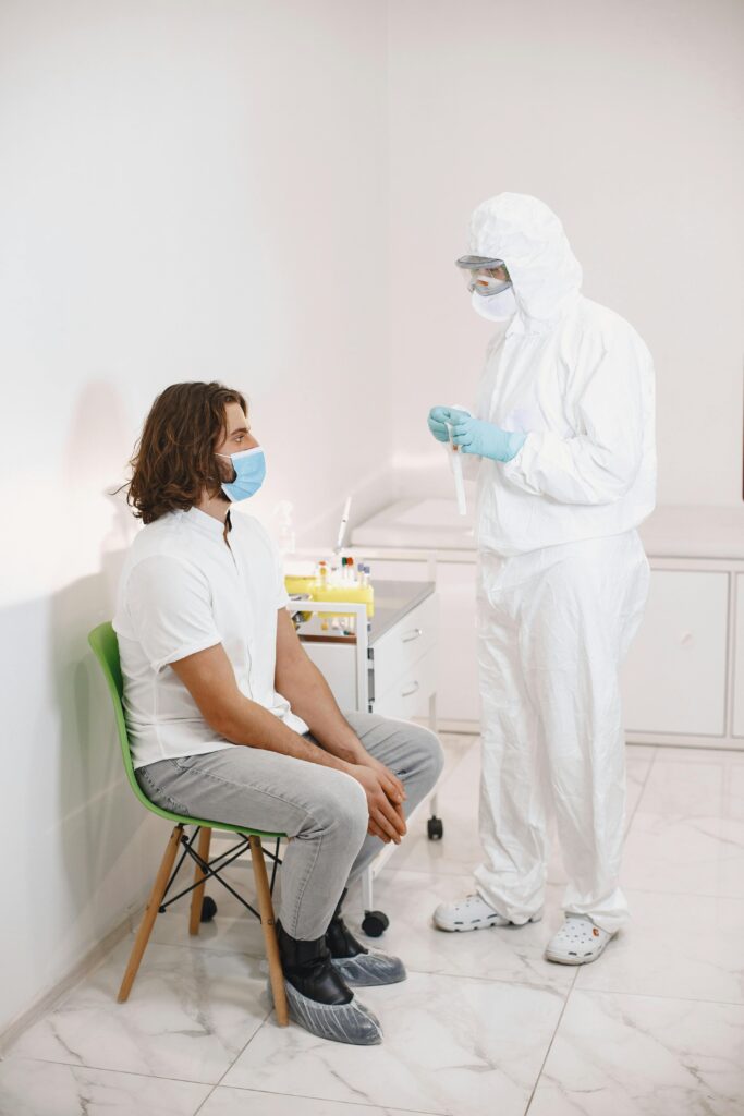 Healthcare worker wearing PPE conducts a COVID-19 test on a patient in a clinical setting.